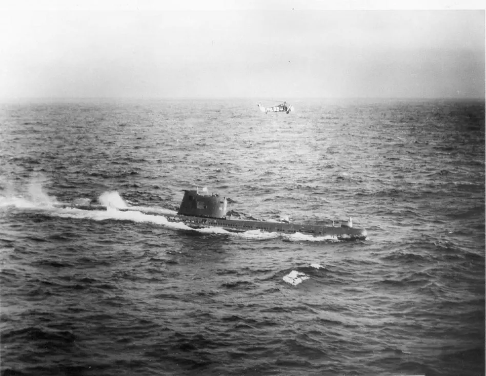 צילום שחור-לבן: הצוללת הסובייטית B-59 על פני המים, צוות על מגדל הפיקוד וכלי טיס אמריקני ברקע